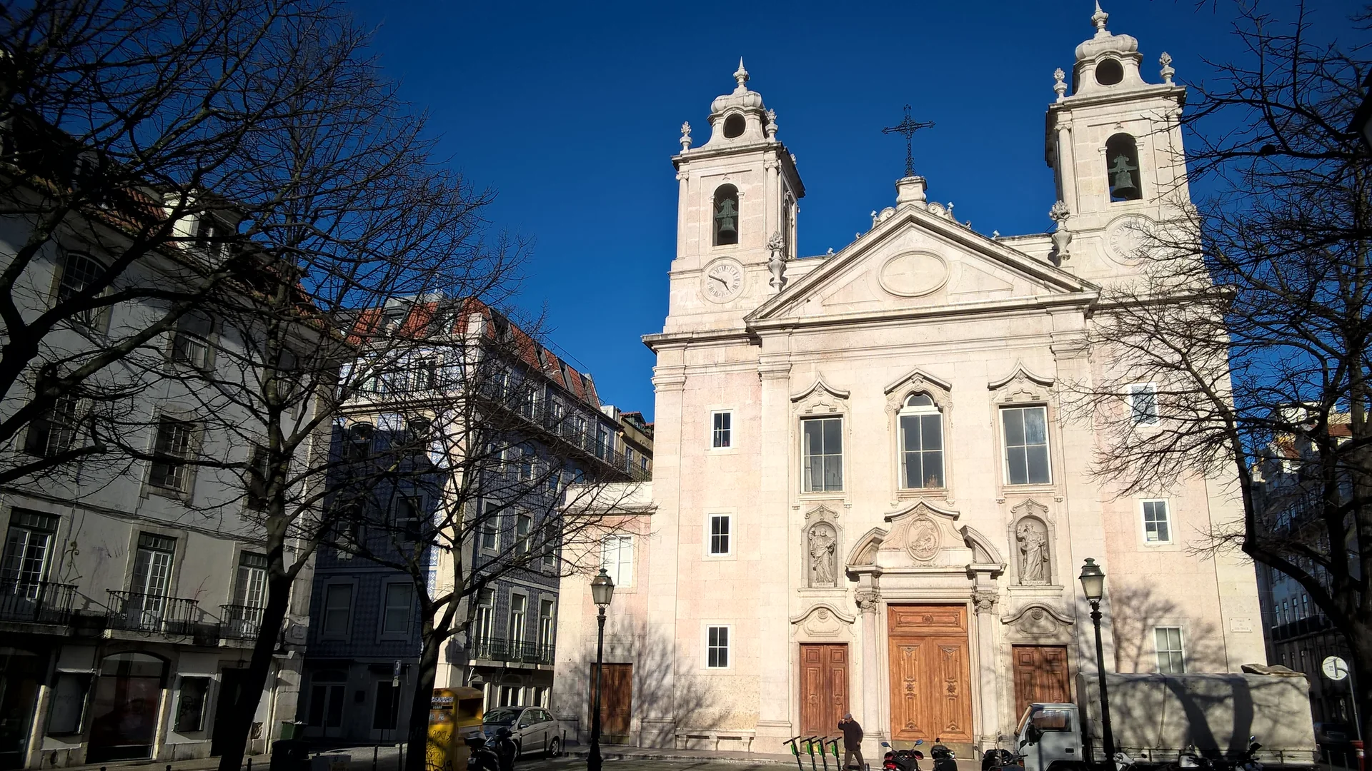 Bledě kamenné průčelí kostela São Paulo v Lisabonu, dvě zvonice nad trojúhelníkovým tympanonem, na pozadí hluboce modré zimní oblohy